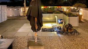 Ein Patio im Freien mit Steinboden, einem Wasserspiel und einer Sitzecke mit Tisch und Stühlen.