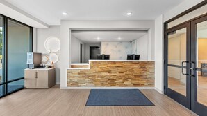 A reception area with a stone wall, a reception desk, a counter, and a door. - Echo Suites Extended Stay by Wyndham Atlanta-Conyers (Conyers)