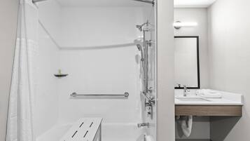 Un bany modern amb plat de dutxa de vidre, banyera, lavabo amb mirall i barra de tovalloles.