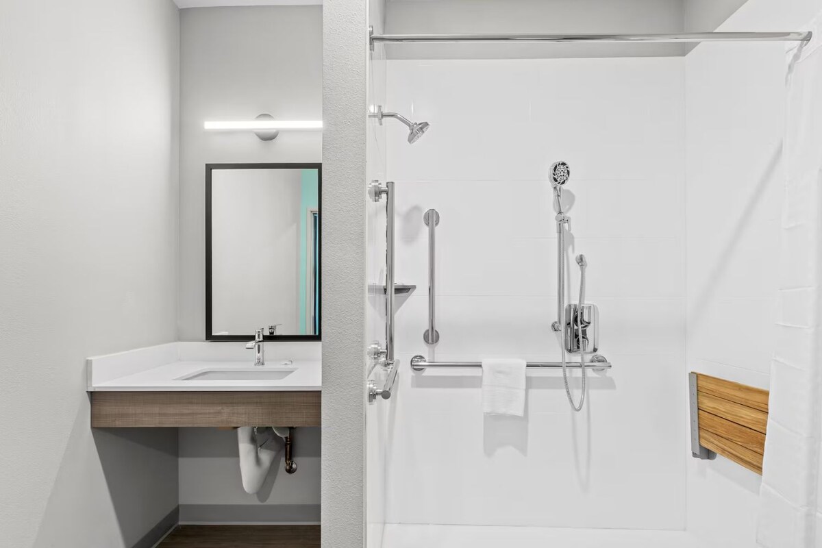 A modern bathroom with a sink, mirror, and shower.