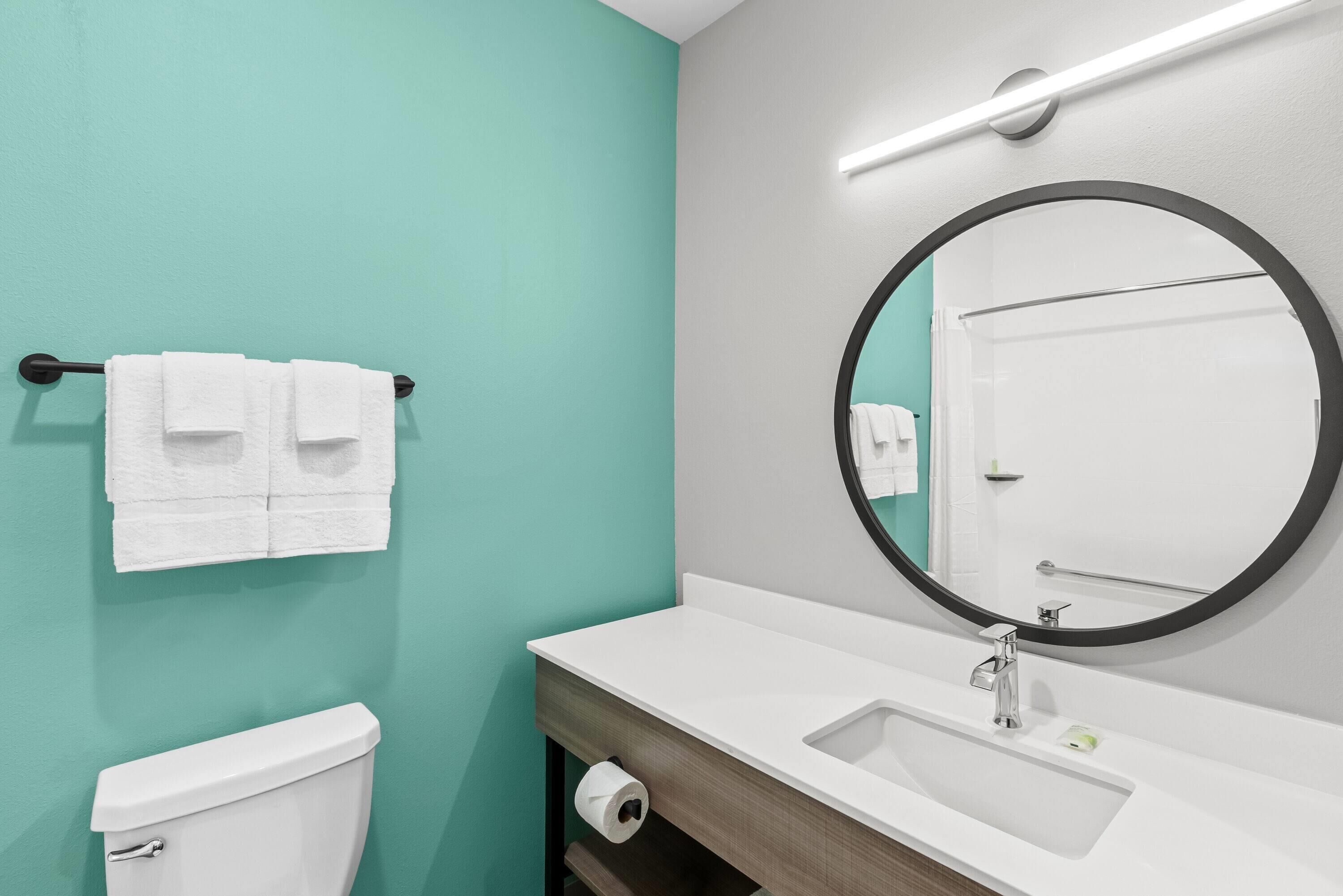 A bathroom with a toilet, sink, and mirror.