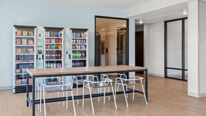 A modern indoor space with a long table and six chairs, surrounded by vending machines stocked with snacks and drinks. - Echo Suites Extended Stay by Wyndham Atlanta-Conyers (Conyers)
