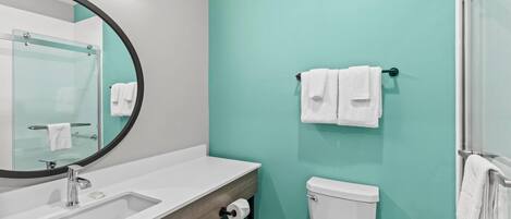 A bathroom with a white sink, a toilet, and a glass shower enclosure.