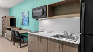 A compact kitchen with a microwave, sink, and a built-in cabinet. - Echo Suites Extended Stay by Wyndham Atlanta-Conyers (Conyers)