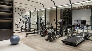 Une salle de sport moderne équipée de divers appareils d’exercice, notamment des tapis de course, des vélos d’appartement et des appareils de musculation.