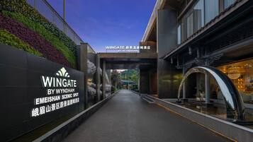 Entrada de hotel con diseño moderno, que presenta un letrero iluminado grande y un arco decorativo.