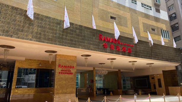 Een hotelentree met een bord waarop 'RAMADA HOTEL' en '华美达酒店' staat.