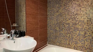 Een badkamer met een wit wastafel, een spiegel en een betegelde muur.