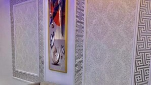 A tufted sofa in a corner with decorative panels and a framed abstract painting on the wall. - White Chase Hotel and Suites (Lagos)