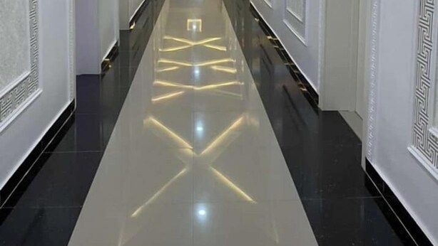 A long, narrow hallway with a reflective floor and recessed lighting. - White Chase Hotel and Suites (Lagos)