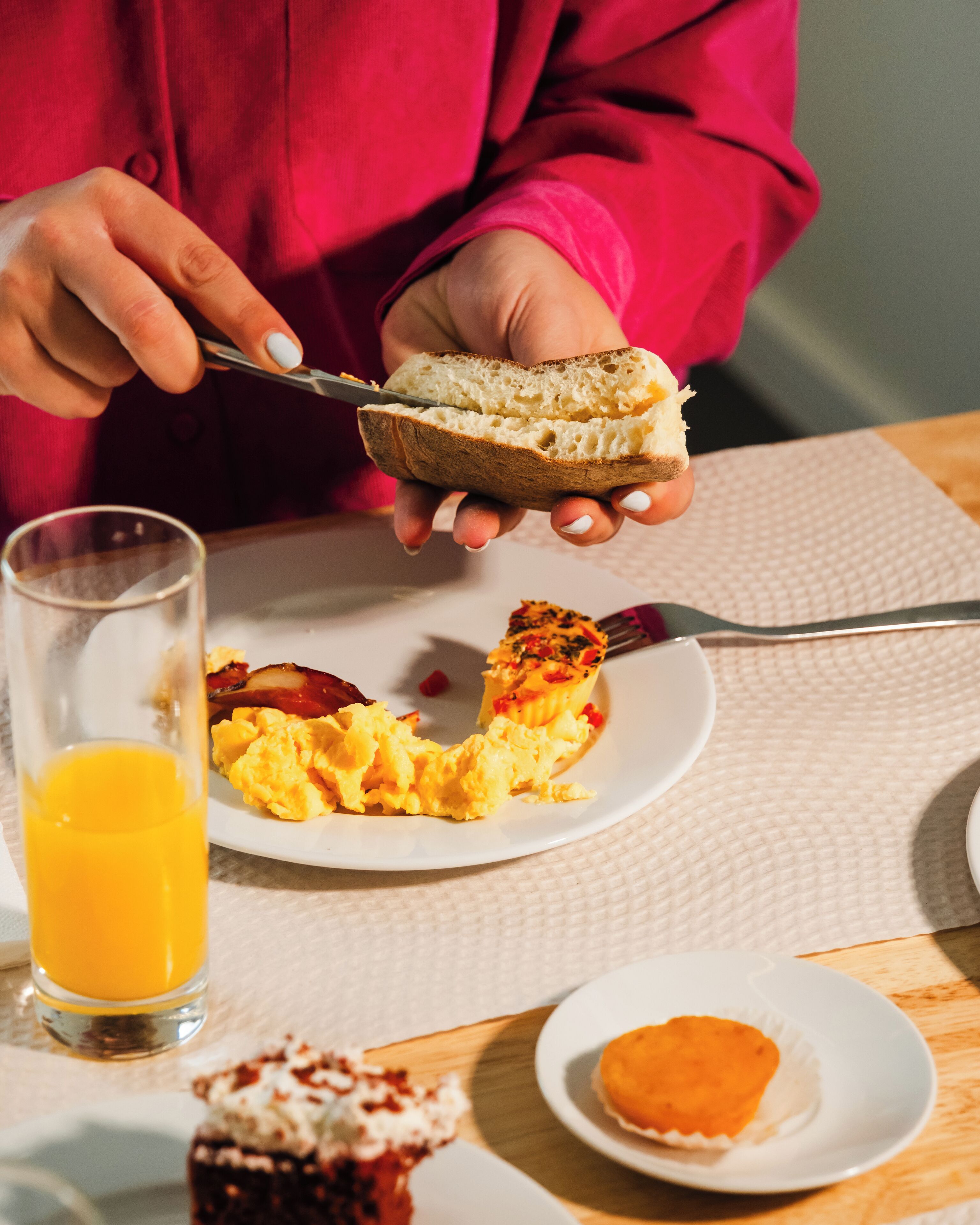 Une table mise pour le petit-déjeuner, avec des toasts, des œufs brouillés et un verre de jus d’orange.