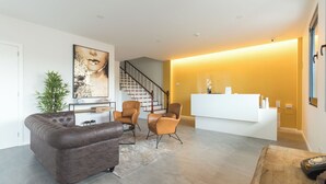 Un salon moderne comprenant un canapé, des fauteuils, un comptoir d’accueil et un escalier.