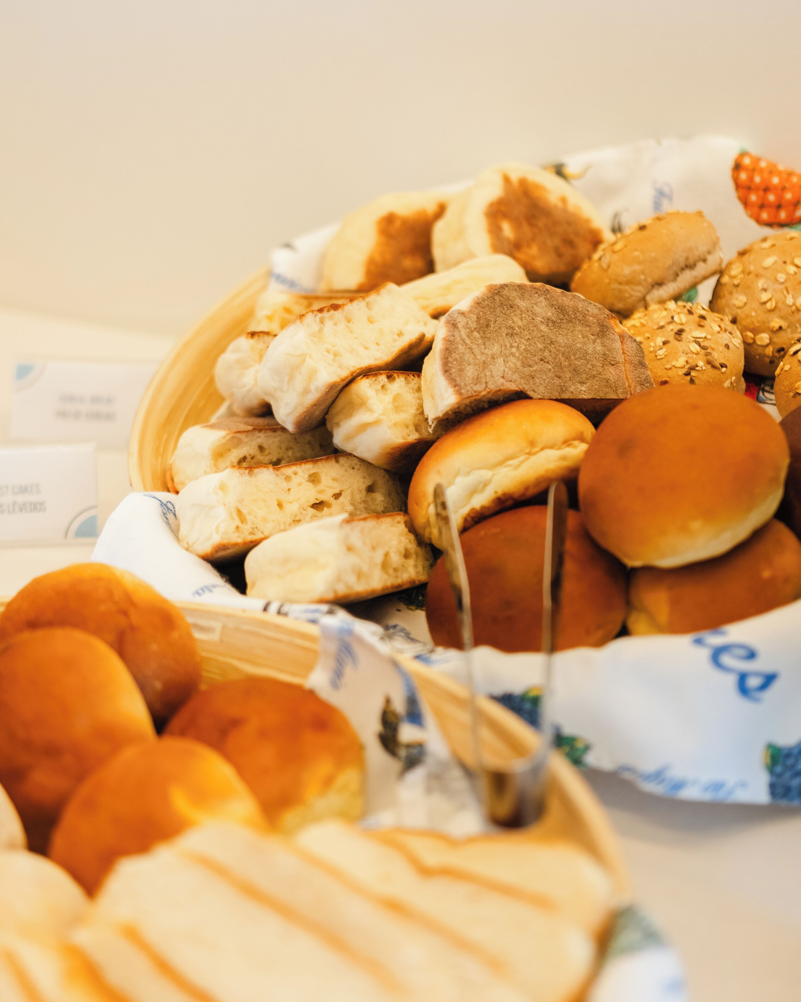 Een mand gevuld met verschillende soorten brood, waaronder broodjes en bolletjes.