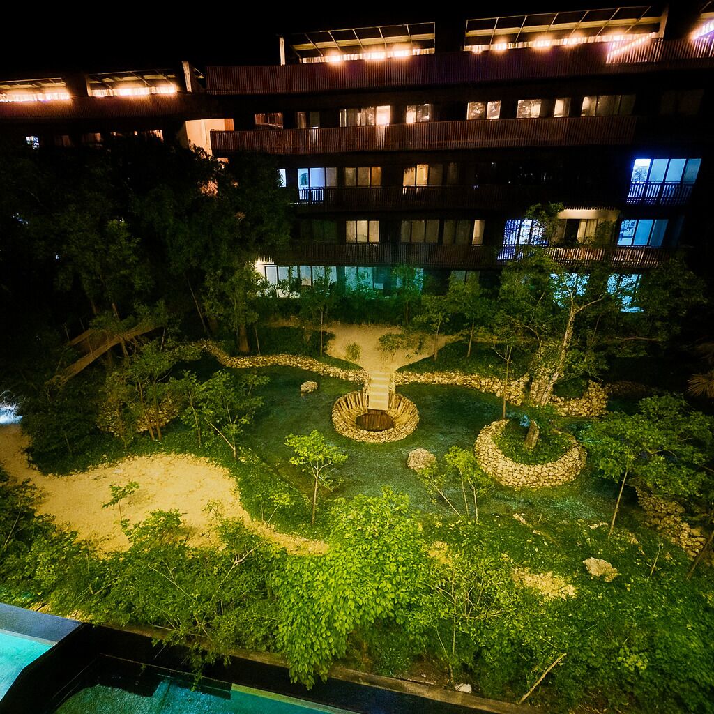 Un edificio de varios pisos con un patio central que presenta una estructura circular de piedra y un camino.