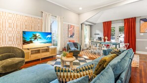 A living room with a television, sofa, armchair, and dining area.