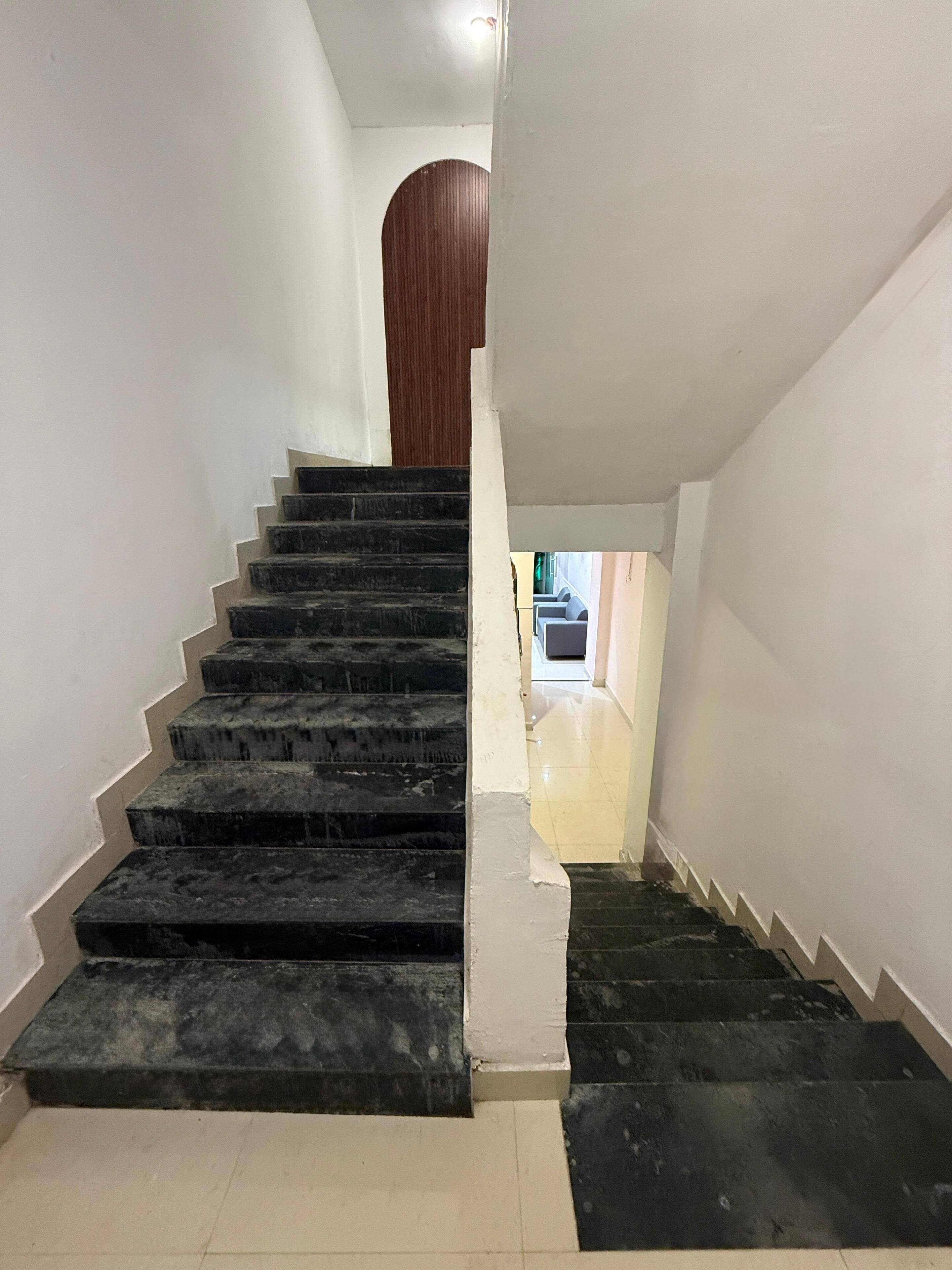 Una escalera con escalones negros que lleva a una puerta de madera en la parte superior.