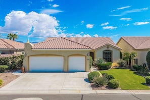 A residential house with a tiled roof, two attached garages, and a well-maintained lawn. - Desert Fairway Oasis (Indio)
