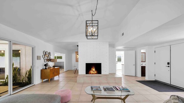 A spacious living room with a fireplace, a glass coffee table, and a sofa.
