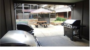 An outdoor patio with a grill, a table with an umbrella, and a stone planter. - 2-bedroom condo in beautiful Park City just in time for Sundance (Park City)