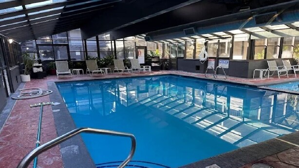 An indoor swimming pool with clear glass walls, lounge chairs, and a covered area with a roof. - 2-bedroom condo in beautiful Park City just in time for Sundance (Park City)