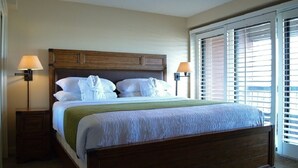 A neatly made bed with white linens and a green throw, flanked by two bedside lamps, in a room with a large window and blinds. - 2-bedroom condo in beautiful Park City just in time for Sundance (Park City)