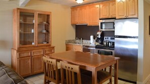 A kitchen with wooden cabinets, a stainless steel refrigerator, a microwave, and a dining table with chairs. - 2-bedroom condo in beautiful Park City just in time for Sundance (Park City)