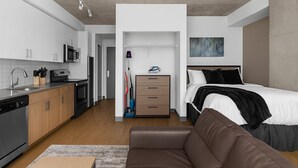 Un appartement moderne et compact, doté d’une kitchenette, d’un lit et d’un espace de vie.
