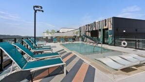 Un espace piscine aménagé sur le toit, avec des chaises longues et une vue dégagée sur le panorama urbain.