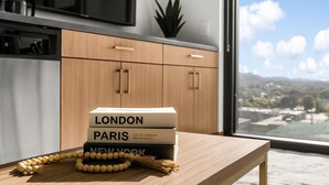 A modern kitchen with wooden cabinets and a view of a cityscape through a large window.