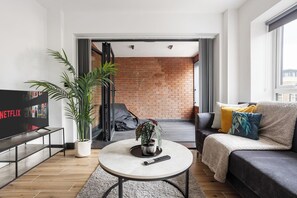 Un salon moderne avec un téléviseur, une table basse, un canapé et un mur en briques.