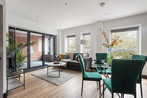 A modern living room with a sofa, chairs, a coffee table, and a dining area with a table and chairs.