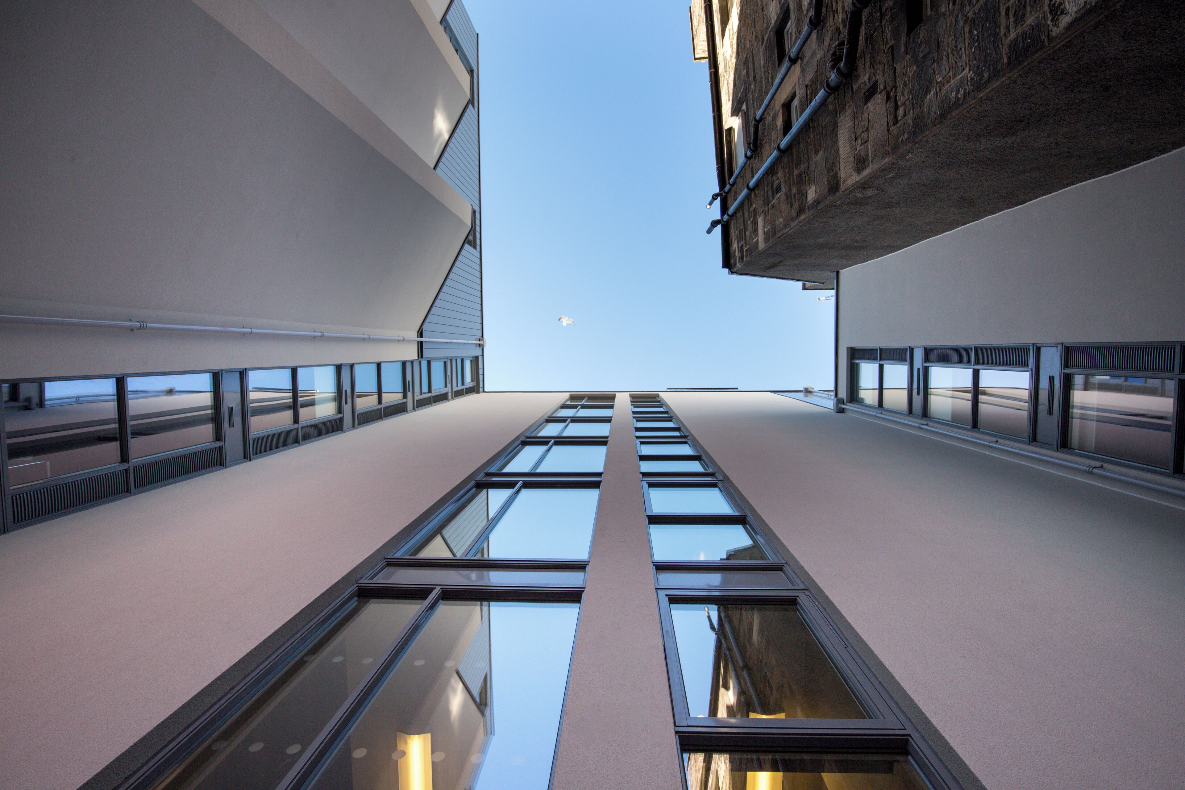 A modern building with a glass facade and a clear sky.