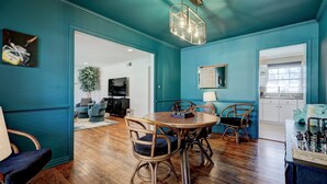 A dining area with a round table and chairs, a chandelier, and a chessboard on a side table.