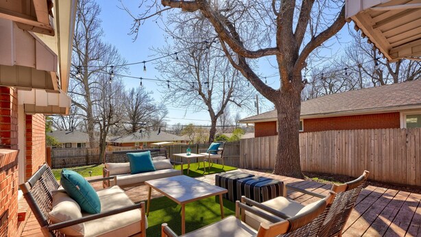 A backyard with a patio area featuring a sofa, chairs, and a table.