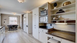 A modern kitchen with white cabinetry, a built-in oven, microwave, and a granite countertop.
