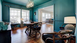 A spacious room with a wooden dining table, chairs, and a large window.