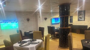 A restaurant with tables set for dining, a large pillar, and a TV screen displaying a sports event.