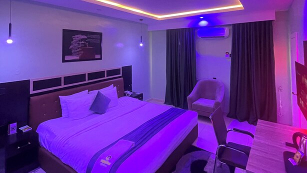 A modern bedroom with a bed, bedside tables, a desk, and a chair.