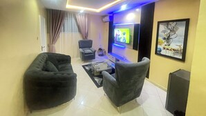 A living room with a flat-screen TV, two armchairs, a sofa, and a coffee table.