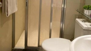 A modern bathroom with a glass shower enclosure, a toilet, and a sink. - Azure Urban Resort Residences (Paranaque)