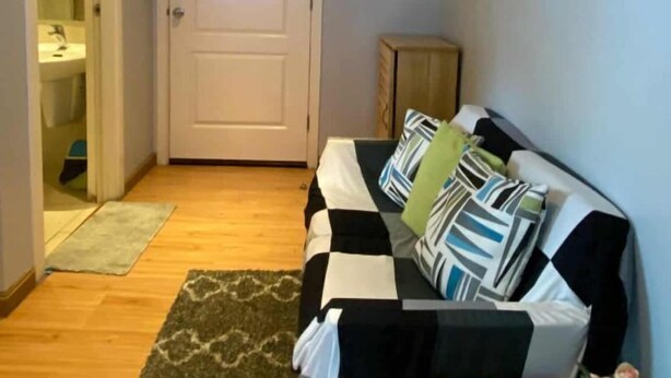 A living room with a sofa, a clock, a door, and a small table with a plant. - Azure Urban Resort Residences (Paranaque)