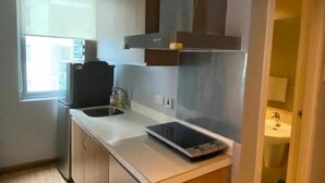A compact kitchen with a built-in oven, a microwave, and a sink. - Azure Urban Resort Residences (Paranaque)