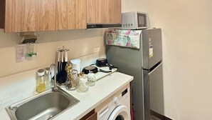 Une cuisine compacte avec des meubles en bois, un lave-linge, un four à micro-ondes et un réfrigérateur.