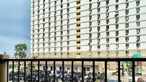 Un échiquier sur un balcon, avec vue sur un parking et un immeuble à plusieurs étages en arrière-plan.