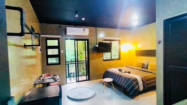 Une chambre d’hôtel moderne avec un lit, un petit bureau, une table ronde et une grande fenêtre.