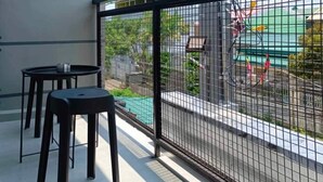 Un balcon avec une balustrade en métal, deux tabourets noirs et une petite table.