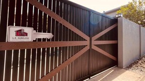 Une entrée fermée par un portail, avec une enseigne indiquant « L.E. Subeldia Construction ».