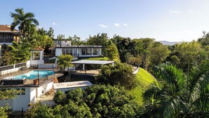 Una casa moderna con piscina, immersa nel verde e circondata da un paesaggio collinare.