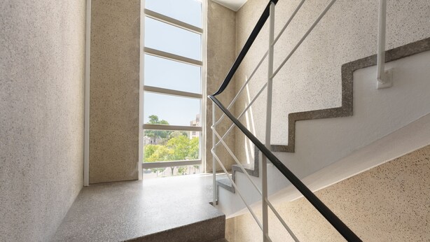 Un escalier doté d’une rampe métallique et offrant une vue sur les arbres à l’extérieur.