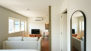 Une chambre d’hôtel moderne dotée d’un grand lit, de deux canapés, d’une télévision, d’un coin repas et d’un grand miroir.